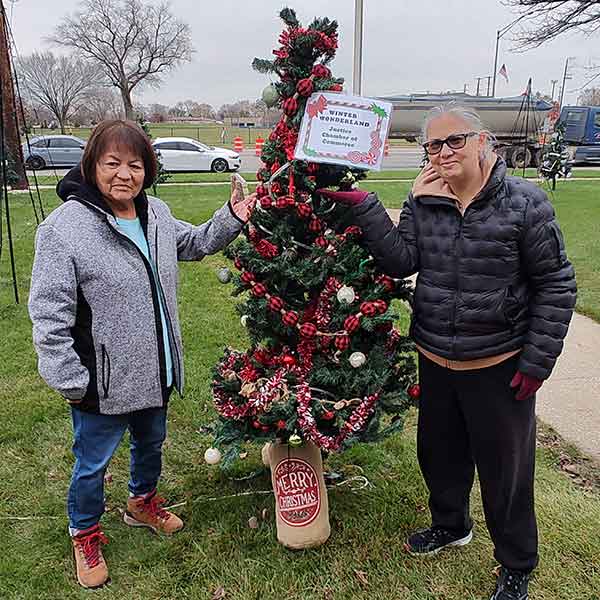 two women posing next to Christmas tree